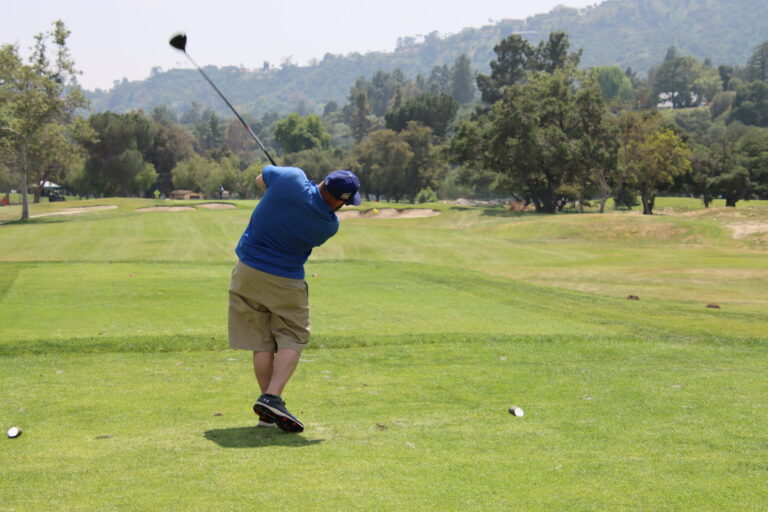 a man in blue tees off towards a green hillside