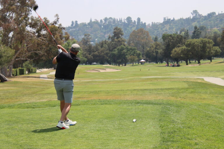 a man in a black shirt and gray shorts teeing off