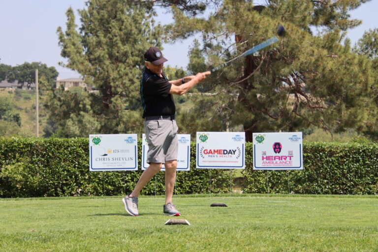 a man teeing off in front of a row of tee signs