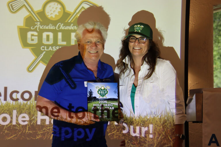 a man in blue holding up a plaque for best hole hero at the Arcadia Chamber golf tournament