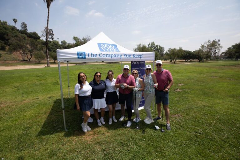 a group of people stand in front of a white tent with the New York Life logo on it