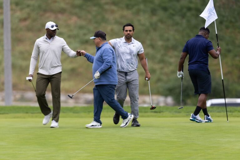 a group of golfers fist bump each other after making a putt