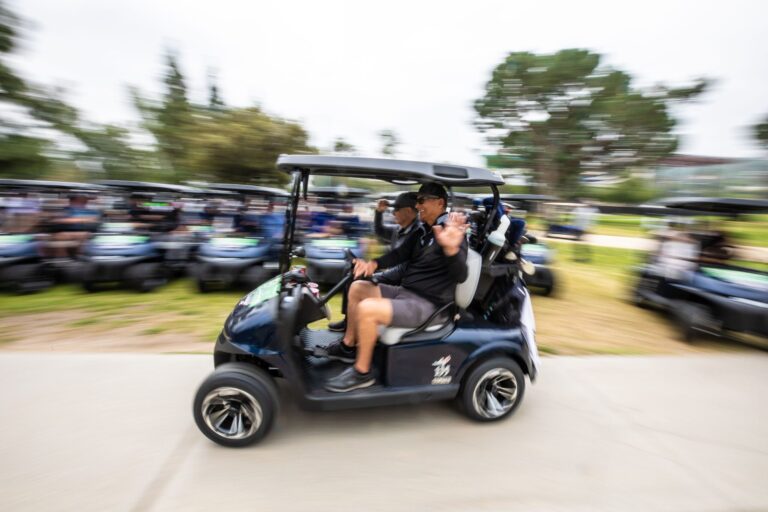 a golf cart whizzing by while the people inside wave and the background is blurred