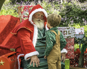 Santa in Victorian costume talking to a small boy in overalls 