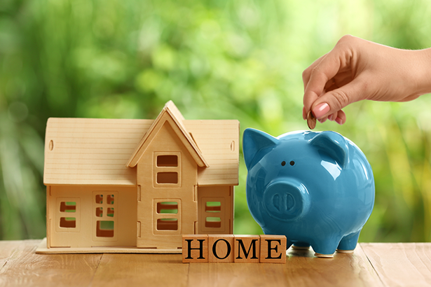 a blue piggy bank sitting next to a small wooden house and a sign with the word home on it
