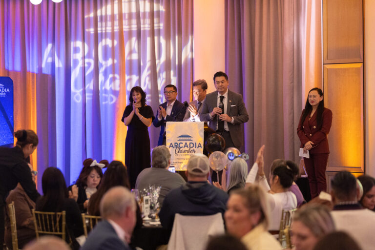 a group of three men and two women on a stage with the Arcadia Chamber logo behind them