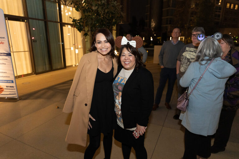 a woman in a brown jacket with a woman in a black sweater and star wars shirt