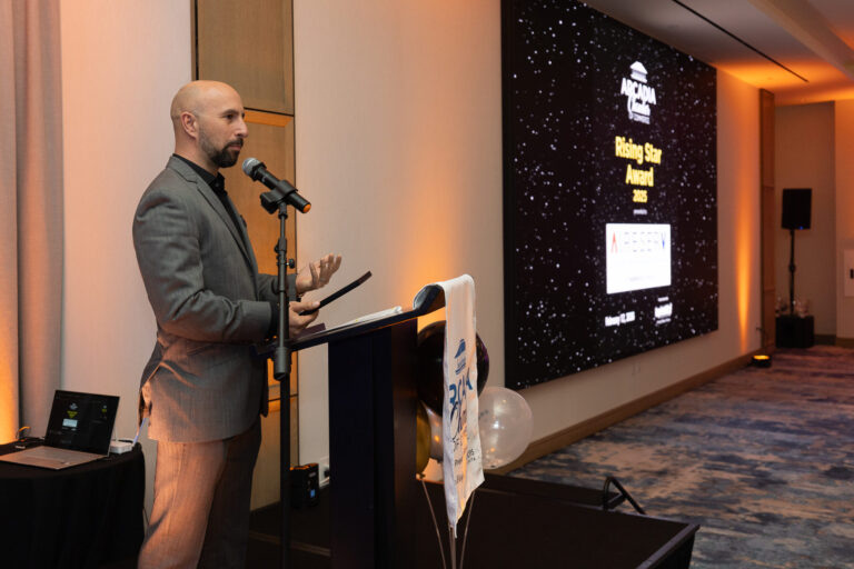 a man in a gray suit standing at a podium giving a speech