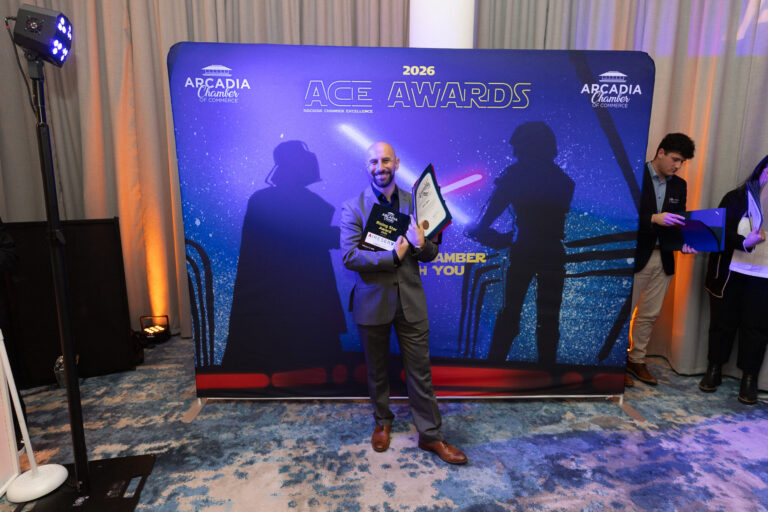 a man holding a plaque and certificates in front of a banner