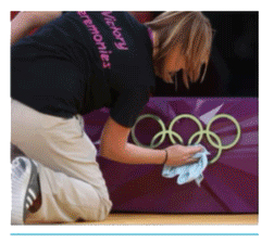 Woman volunteer cleaning Olympic banner.