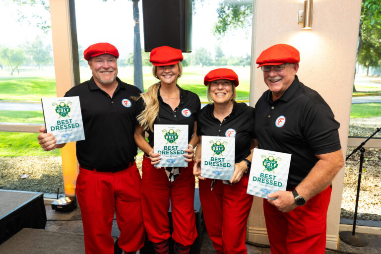 a group of two women flanked by two men dressed in red and black golf attire all holding plaques