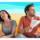 two people fanning themselves against a colorful waving background