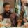 a man staring at a skewer of meats at Fogo de Chao