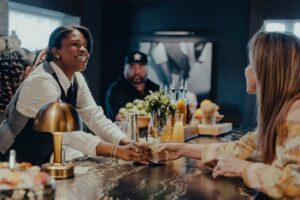 a waitress handing a drink across a bar to a customer