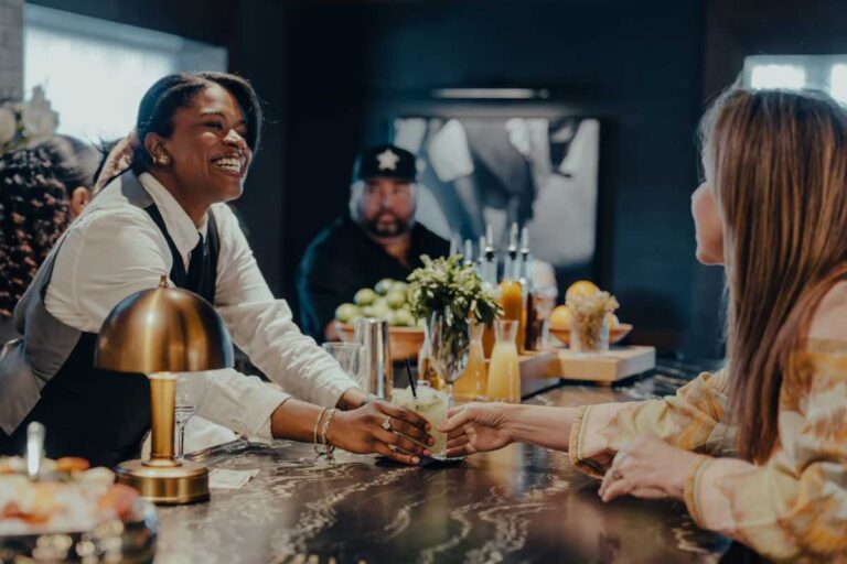 a waitress handing a drink across a bar to a customer