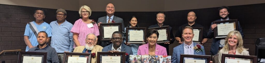 Judy Chu seated with a group of people all holding up awards