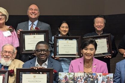 Judy Chu seated with a group of people all holding up awards