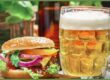 a burger sitting next to a glass of beer
