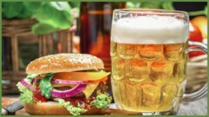 a burger sitting next to a glass of beer