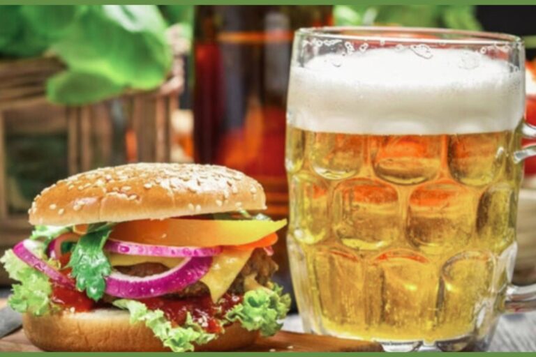 a burger sitting next to a glass of beer