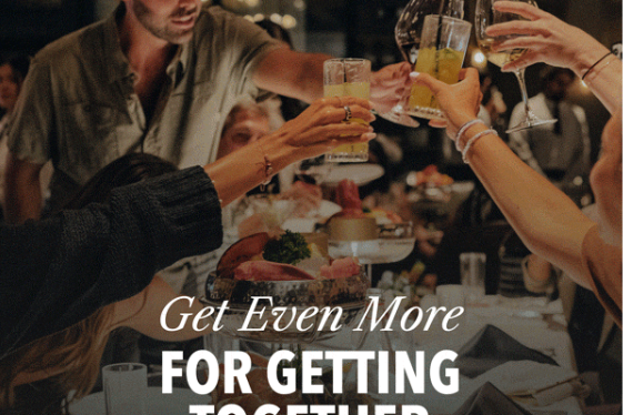 a group of people at Fogo de Chao raising glasses to cheers over a spread of food